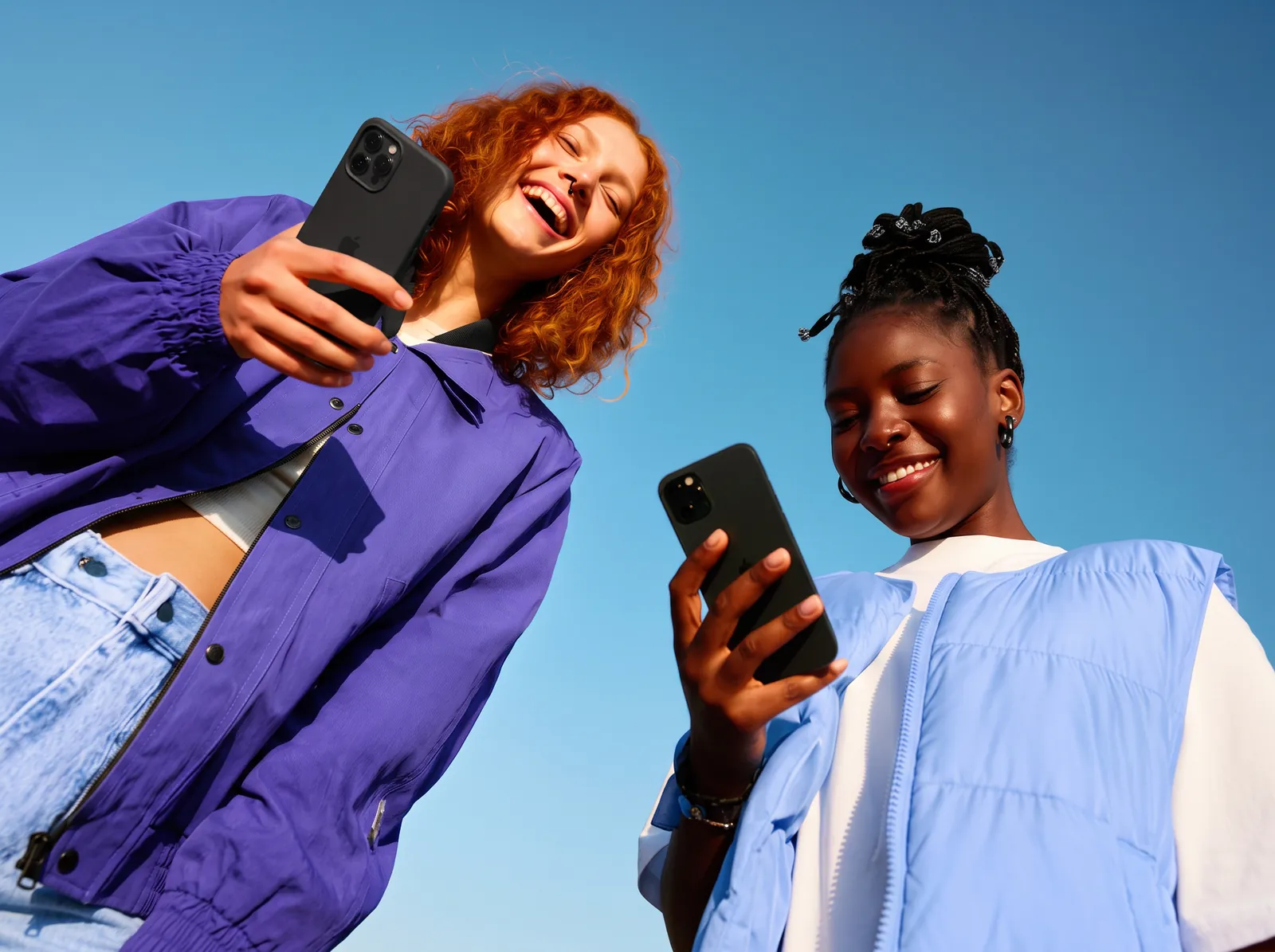Duas amigas rindo enquanto olham oportunidades no celular